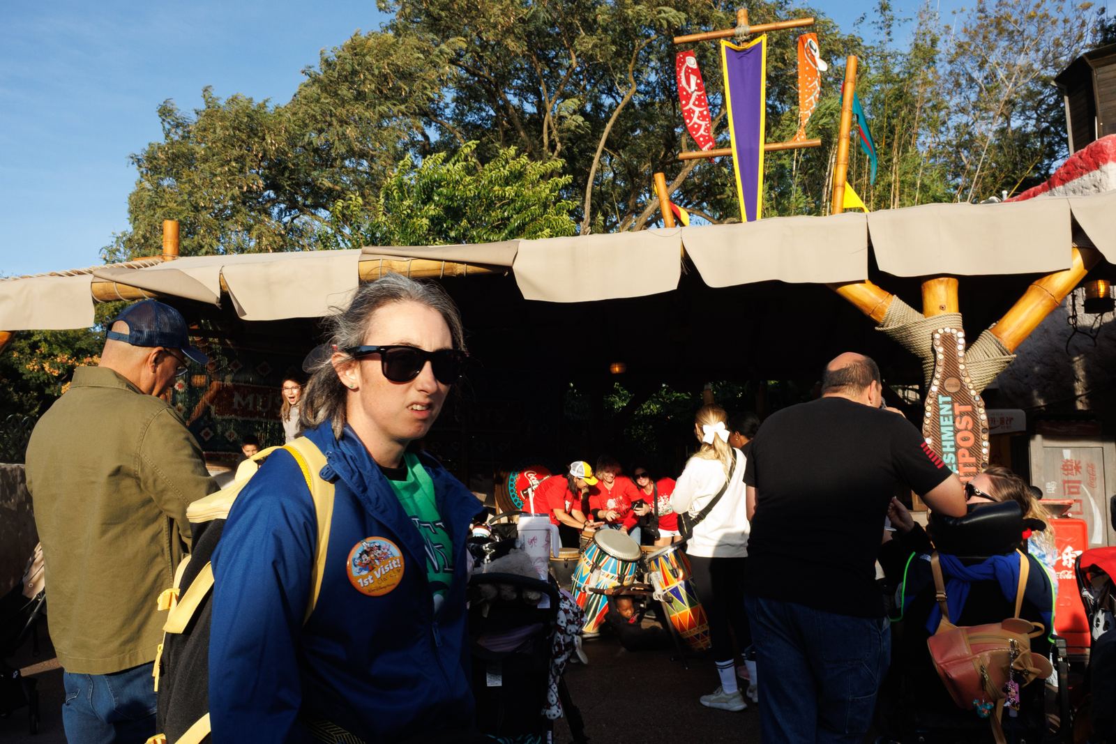 A woman crossing a busy gathering beside colorful drums