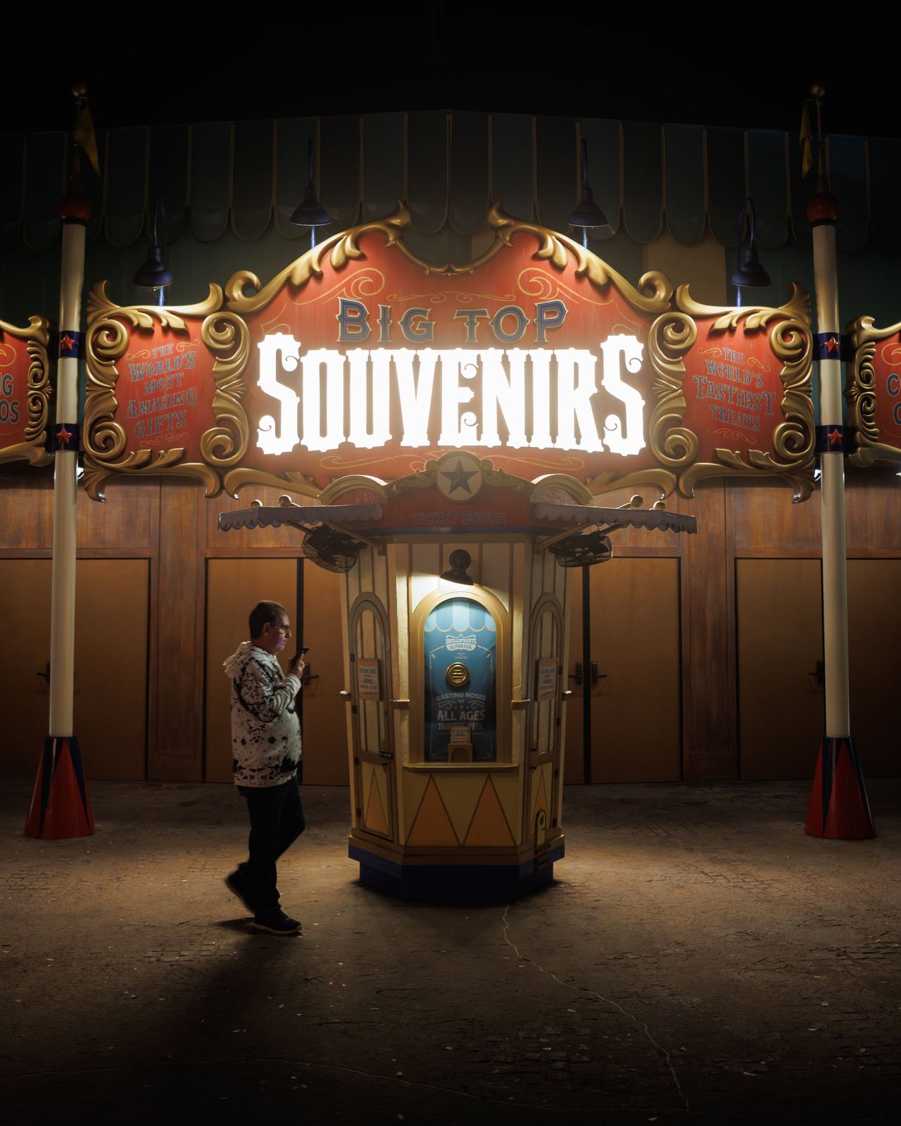 A lone figure walking past a glowing souvenir booth