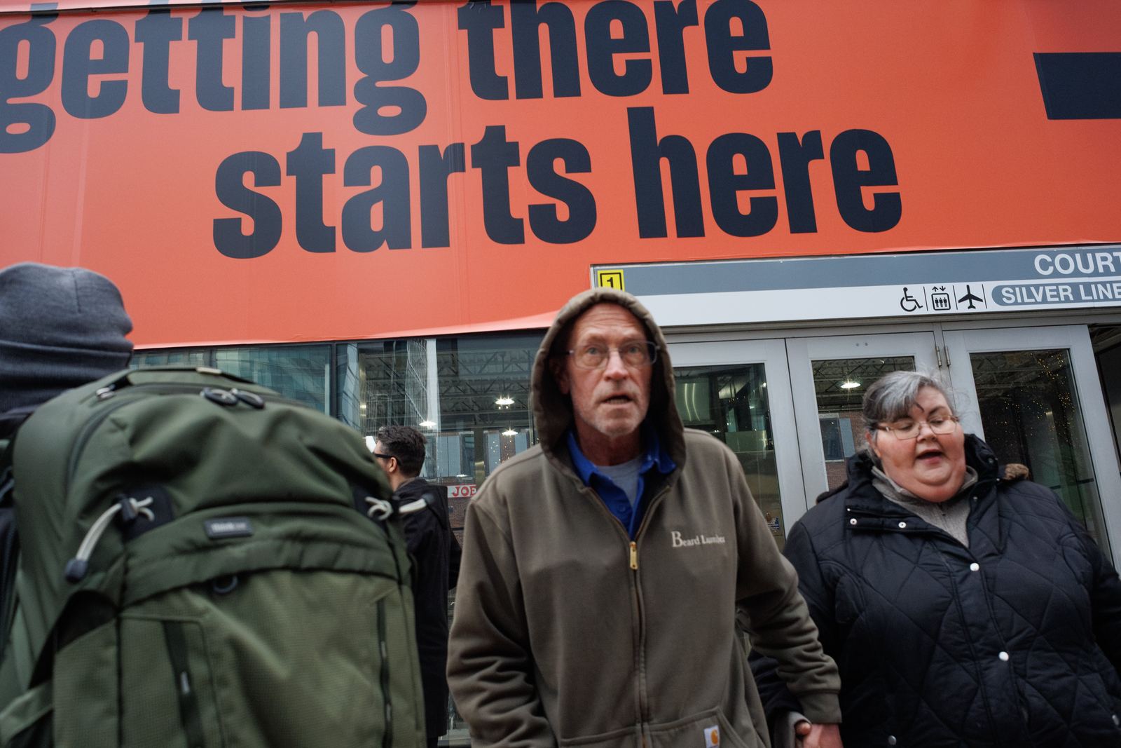 Pedestrians beneath a large orange sign