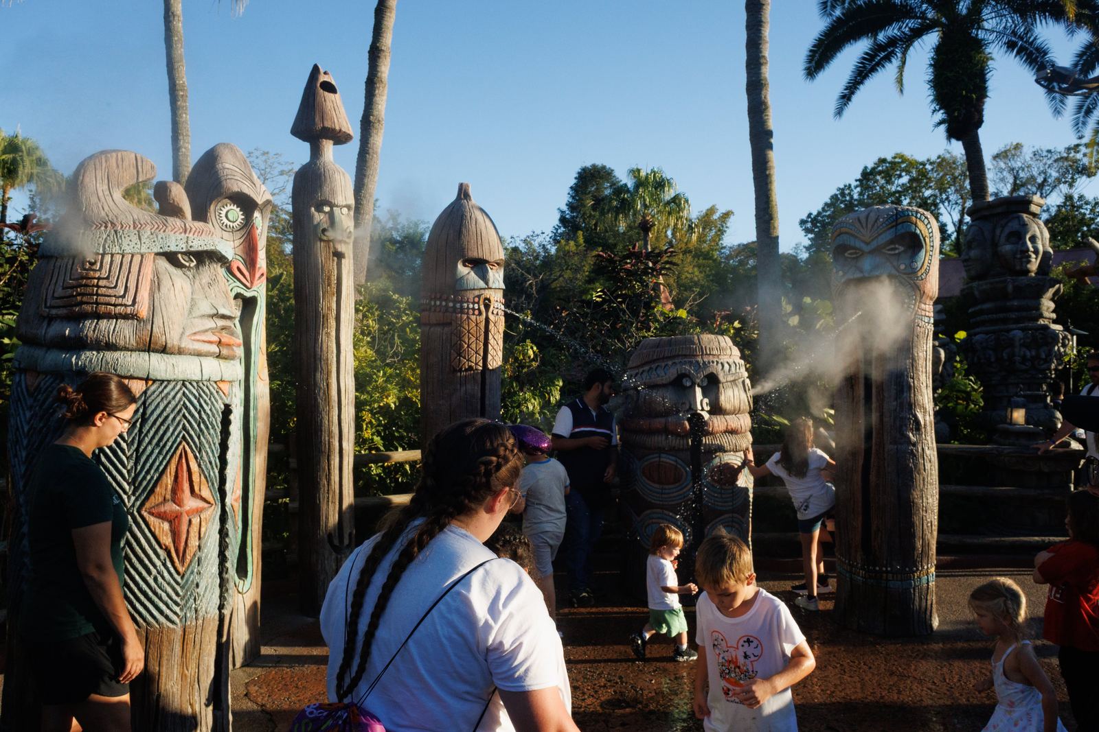 People moving among carved figures and drifting mist