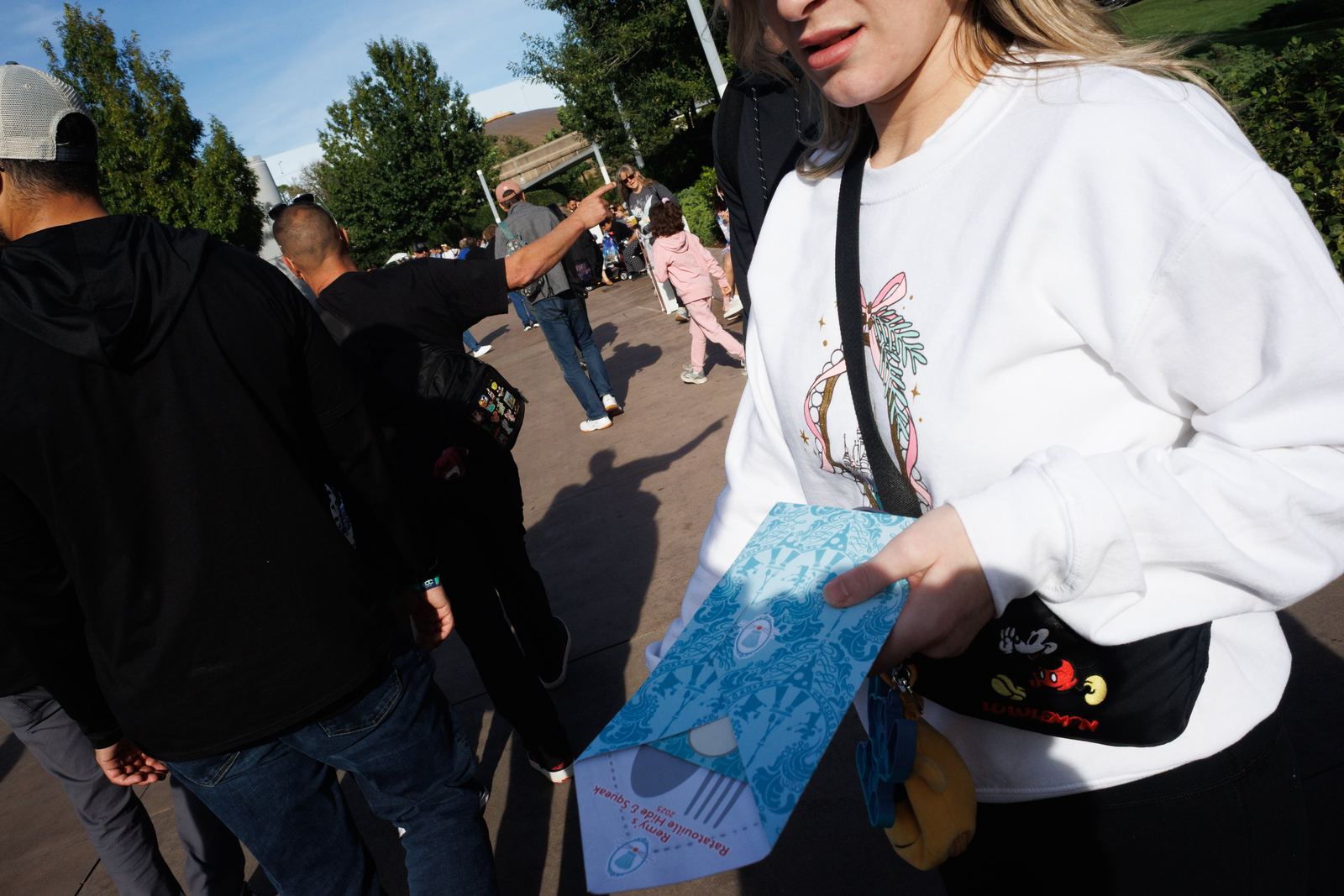 A close passing figure carrying a blue paper in a crowd